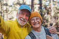 Head shot portrait close up of cute couple of old seniors taking a selfie together in the mountain forest looking at the camera Royalty Free Stock Photo