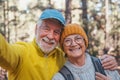 Head shot portrait close up of cute couple of old seniors taking a selfie together in the mountain forest looking at the camera Royalty Free Stock Photo