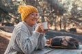 Head shot portrait close up of middle age woman relaxing drinking coffee or tea sitting at table in the forest of mountain in the Royalty Free Stock Photo