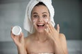 Head shot portrait funny young woman holding face cream jar