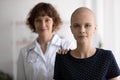 Head shot portrait hairless woman standing with doctor behind back
