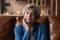 Head shot portrait mature woman sitting on couch alone