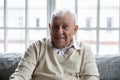 Old healthy positive grandfather sitting on couch looking at camera