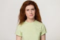 Redhead woman feels confused suspicious pose over grey studio background