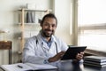 Head shot portrait smiling African American man doctor holding tablet Royalty Free Stock Photo