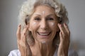 Head shot portrait smiling beautiful mature woman applying cream Royalty Free Stock Photo