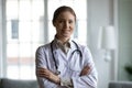 Head shot portrait smiling female doctor with arms crossed