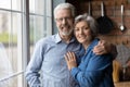 Head shot portrait smiling mature couple hugging, standing in kitchen Royalty Free Stock Photo