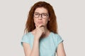 Head shot portrait of thoughtful millennial red-haired woman.