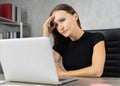 Head shot serious Caucasian businesswoman tired and touch head while working with computer, book shelf and copy space at Royalty Free Stock Photo