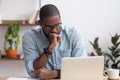 Head shot serious puzzled African American businessman looking at laptop