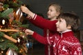 Happy excited small kids decorating Christmas tree with baubles.