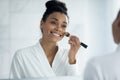 Head shot smiling African American woman applying blush on cheeks