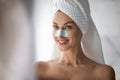 Head shot smiling woman with anti blackhead mask on nose