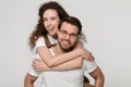 Young man in eyeglasses giving piggyback ride to happy attractive woman. Royalty Free Stock Photo