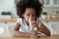 Thirsty small curly african american little child girl drinking water. Royalty Free Stock Photo