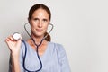 Head shot of woman professiona medical worker wearing blue medical coat holding stethoscope, portrait Royalty Free Stock Photo