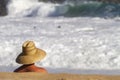 Head and shoulders of Lifeguard with straw hat looking at white water from a large wave