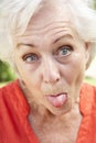 Head And Shoulders Portrait Of Senior Woman Poking Out Tongue Royalty Free Stock Photo
