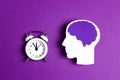 Head silhouette with a purple brain and white alarm clock on a purple background