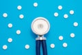 Head of stethoscope is on blue background surrounded by pills or tablets with ornament of polka dots. Concept photo diagnosis, tre