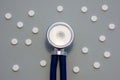 Head of stethoscope is on gray background surrounded by pills or tablets with ornament of polka dots. Concept photo diagnosis, tre