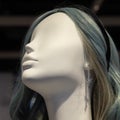 The head of a white female mannequin with gray-blue hair with a silver earring in the ear and a black headband. Closeup Royalty Free Stock Photo