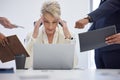 Headache, burnout and overwhelmed business woman surrounded in busy office with stress, paperwork and laptop. Frustrated