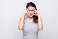 Portrait of unhappy sad beautiful young brunette woman with makeup and striped dress standing, holding head with headache or Royalty Free Stock Photo