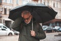 Headache in a mature man outdoors. Senior man under umbrella during doja with migraine Royalty Free Stock Photo