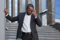 Headache and migraine in businessman, afro-american man in business suit sick near office building holding his head Royalty Free Stock Photo