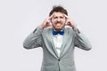 Headache. Portrait of sick or worry bearded man in casual grey suit and blue bow tie standing and holding his painful head with Royalty Free Stock Photo