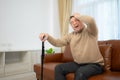 senior guy sits on a sofa with a walking stick in his living room at home Royalty Free Stock Photo