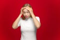 Headache. Tired young girl feeling unhealthy, suffer unbearable migraine flu symptom on red studio background Royalty Free Stock Photo