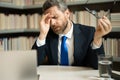 Headache, tiredness and stress. Business man in suit uses a laptop, is tired got headache migraine. Headache pain Royalty Free Stock Photo