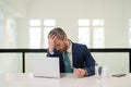 Headache, tiredness and stress. Business man in suit uses a laptop, is tired got headache migraine. Headache pain Royalty Free Stock Photo