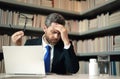 Headache, tiredness and stress. Man in suit uses a laptop, is tired got headache migraine. Headache pain concept