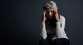 Headaches come and go. Studio shot of a stressed out elderly woman sitting down with her eyes closed and contemplating. Royalty Free Stock Photo