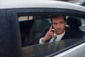 Headed into the office. a businessman sitting in the backseat of a car talking on his cellphone. Royalty Free Stock Photo