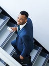 Headed up to the office. A handsome african american businessman using his smartphone while walking up the stairs. Royalty Free Stock Photo