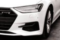 The headlamp of the new clean white sports car is of aggressive form with a part of the bonnet and black wheel, bumper Royalty Free Stock Photo