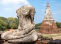 Headless and armless statue of Buddha seated in lotus position made of stone, stupa made of brick behind. Thai Buddhist temple in