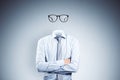 Headless invisible businessman with folded arms and abstract glasses standing on gray wall background. Business concept Royalty Free Stock Photo