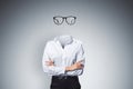Headless invisible businesswoman with folded arms and abstract glasses standing on gray wall background. Business and secret Royalty Free Stock Photo