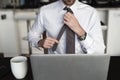 Headless man adjusting tie at desk