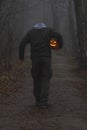 Headless man with Halloween pumpkin in foggy forest