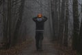 Headless man with Halloween pumpkin in foggy forest