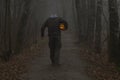 Headless man with Halloween pumpkin in foggy forest