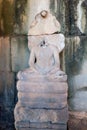 A headless sculpture of Buddha sitting in the lotus position in a Cambodian temple