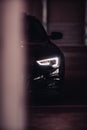 Headlight of a black Audi A5 S-Line car in a parking garage.